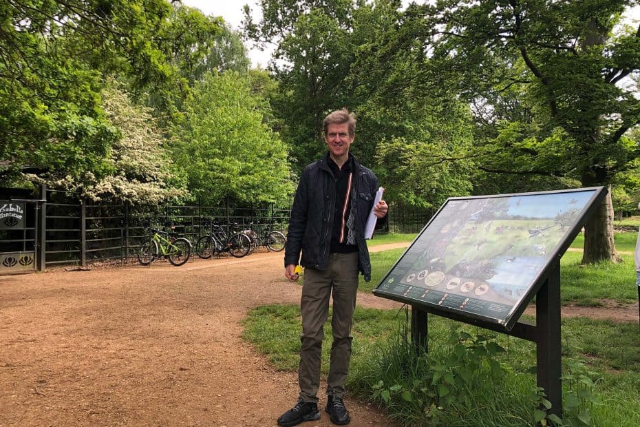 Liam Proudlock standing next to a wayfinding board during an access audit of the Royal Parks