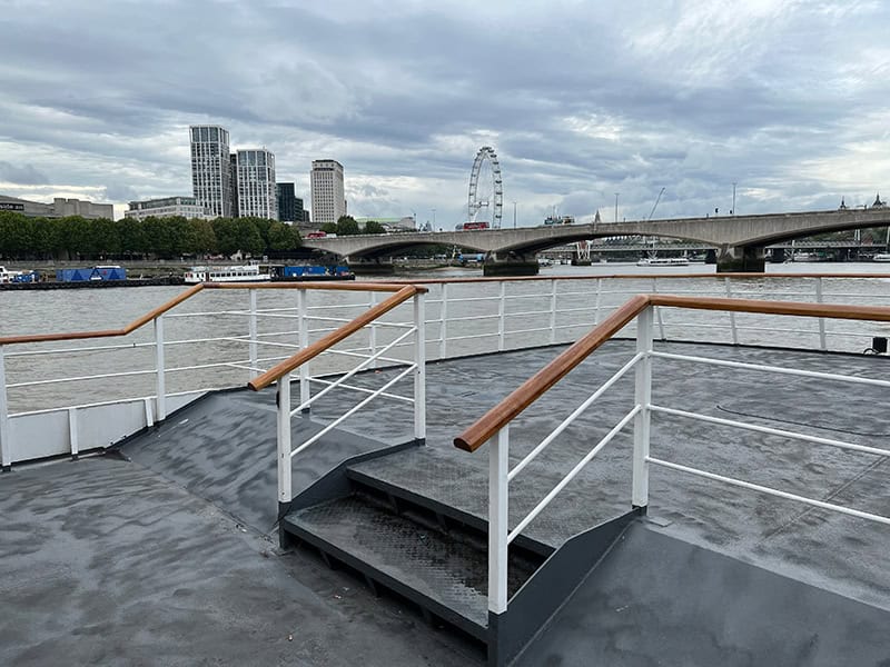 Steps on a the deck of a boat with the London skyline in the background