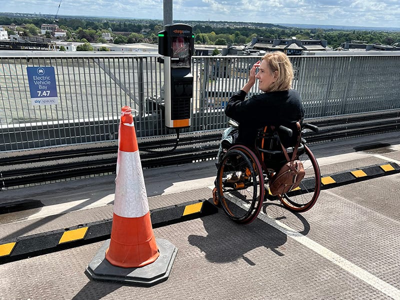 Tracey on roof of car park next to a traffic cone.