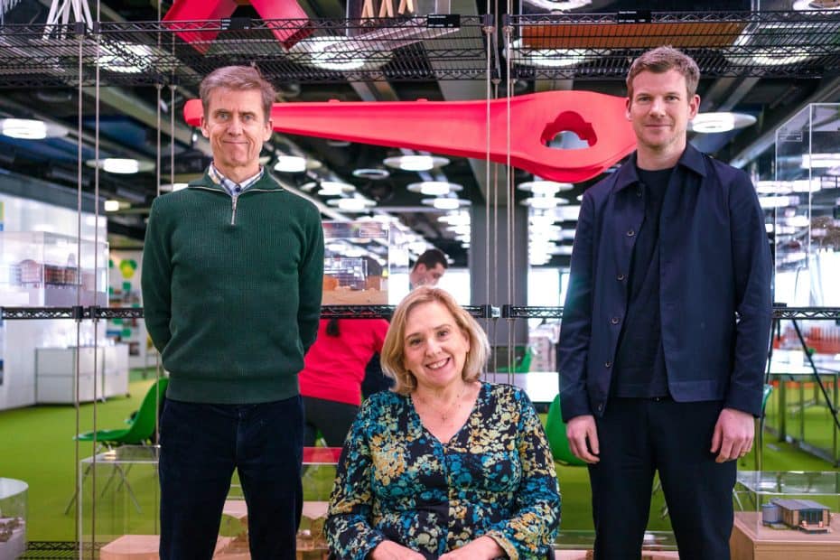 Liam Proudlock, Tracey Proudlock and Mark Rintoul are all in front of a glass door smiling at the camera. There is a red object at head height in the background.
