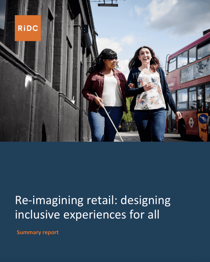 Screenshot of the front cover of the summary report. The RiDC logo is in the top left-hand corner. At the top is a photo of a blind black woman with long black hair wearing dark glasses and holding a white cane. She is wearing a burgundy jacket, white t-shirt and jeans. She is holding the arm of a white woman with long brown hair who is smiling. She is wearing a blue cardigan, flowery top and jeans. They are walking down the street. There is a building to the left of them and a red double decker bus to their right. At the bottom on a dark blue background are the words Re-Imagining retail: designing inclusive experiences for all. Summary report.
