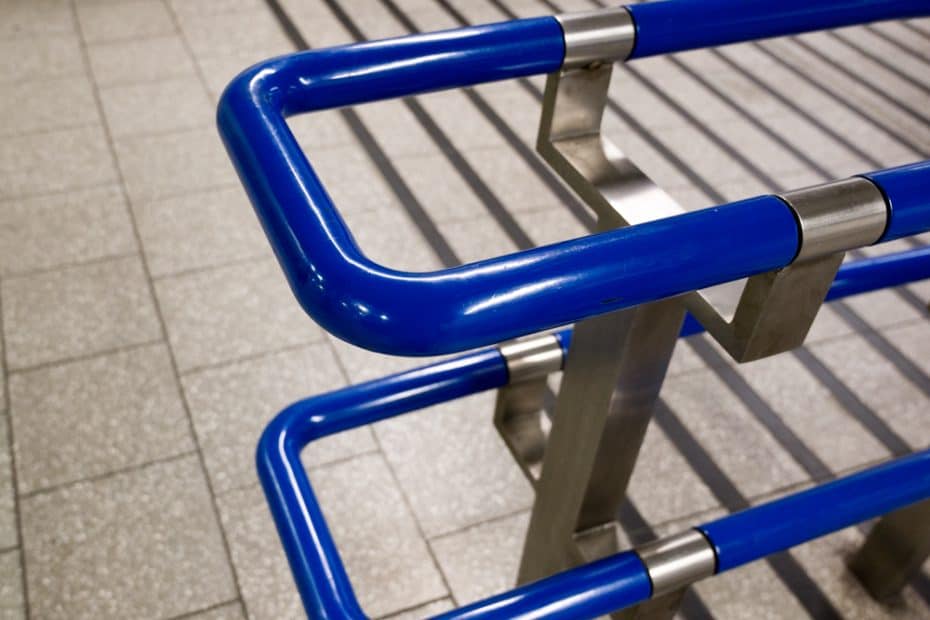 Photo of a bright blue handrail contrasted against a grey tiled floor.
